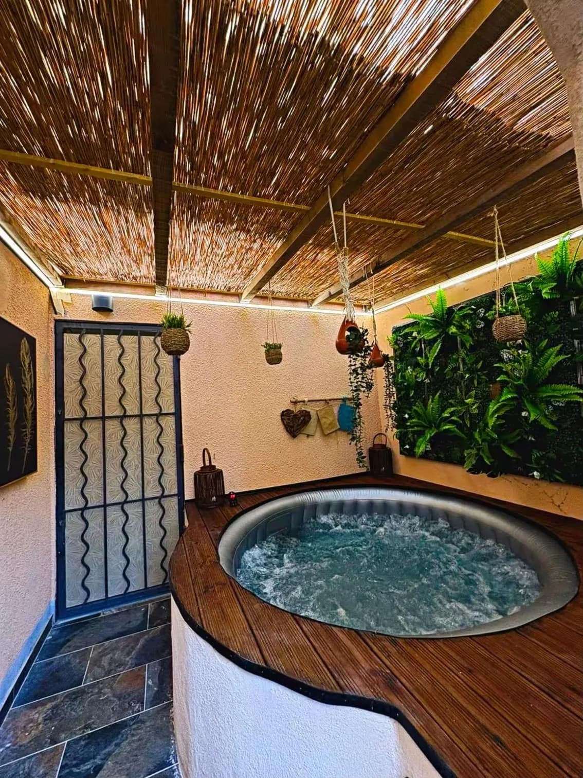 Le jacuzzi privatif du Cabanon sous sa pergola en canisse, éclairé le soir